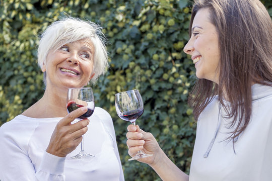 Mother And Adult Daughter Tasting Wine Sitting Outdoor