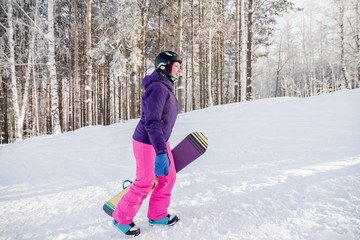 Fototapeta na wymiar Girl in purple jacket and pink pants with snowboard in the hands