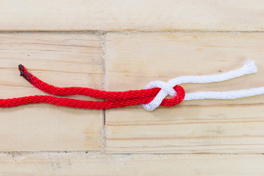 sheet bend knot made with red rope on wooden background.