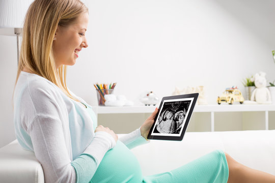 Pregnant woman using tablet to look at sonography results