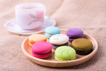 Colorful French Macarons On Wooden background and hot tea