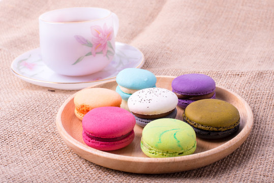 Colorful French Macarons On Wooden background and hot tea