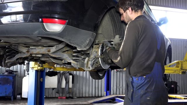 specialist mechanic repairing customer car brake system.