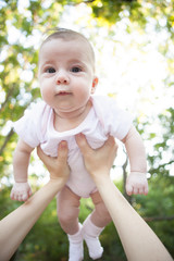 Mother holding cute baby against green trees background