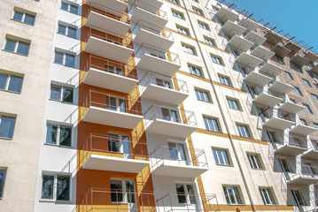 new multistory residential building in the background, decorated in orange and yellow colors in sunny day