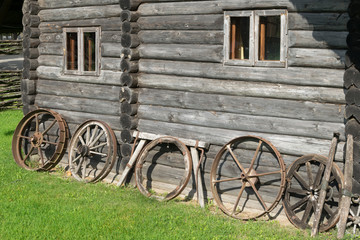 Obraz premium Old wooden wheels to the wall of the house