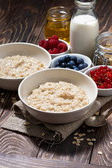 homemade oatmeal and berries on wooden background, vertical