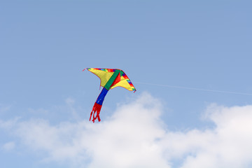 Kite with colourful design flying in sky on sunny day