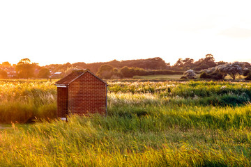 Red brick shed on open land at sunset