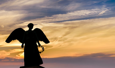 Angel sculpture on sunset background