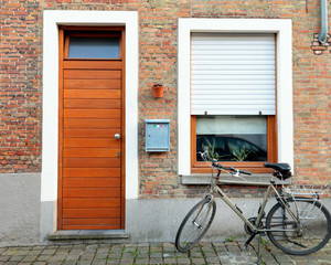 Fototapeta na wymiar Typical european old street - pebble pavement, wooden door of apartment and bicycle.