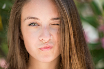 Obraz premium Beautyful lady w headshot, bardzo czysta skóra i piękne funkcje. Zielone liście i różowe kwiaty jako tło