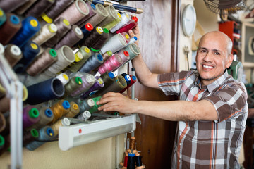 Mature  workman sewing leather boots on stitch lathe