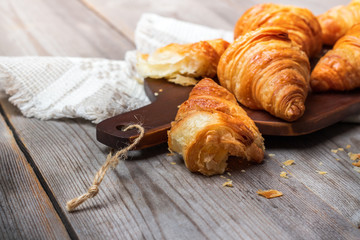 Fresh croissants for breakfast on cutting board rustic table