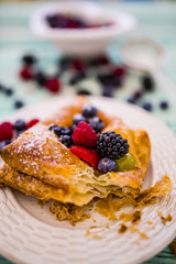 Delicious puff pastry with forest fruit on wooden table. 