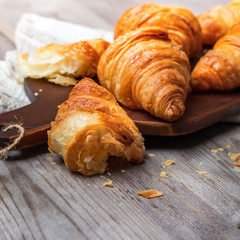 Fresh croissants for breakfast on cutting board rustic table