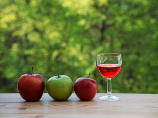 Wine glass  red and  green apples on table