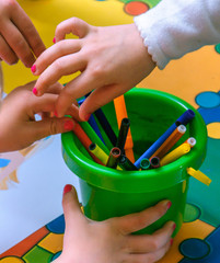 The hands of children hold pencils. Closeup