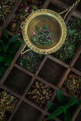 verschiedene sortierte Teesorten in einem Holzkasten mit einem Teesieb