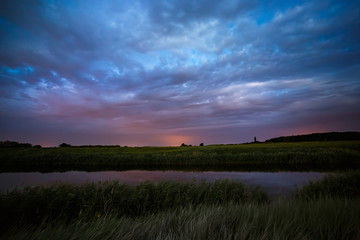 Storm clouds in the sky after sunset on the river.