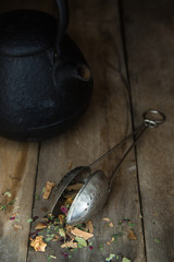 Teefilter mit Tee und einer Teekanne auf einem alten rustikalen Holztisch