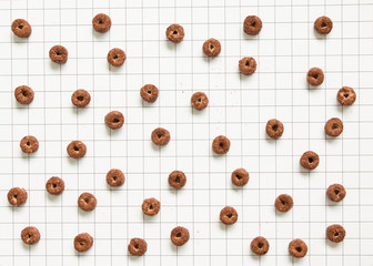 Top view of chocolate cereal pattern on grid pattern background.