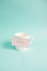 Good Luck on paper note with cup of coffee cup. Side light.
