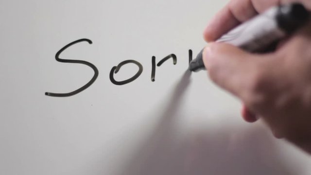 Hand writing title "SORRY" using a black marker on a white board