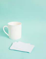 Blank name card mock up and coffee cup on blue background. Side light