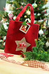 Red bag with  inscription Merry Christmas on the background of Christmas tree. - 121356922