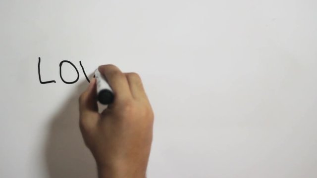 Hand writing a "love is rare" message on a white board using a black marker