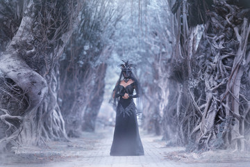 Woman in mysterious place,creative mask and long black dress create dramatic atmosphere