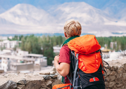 Backpacker tourist looks on blue mountain