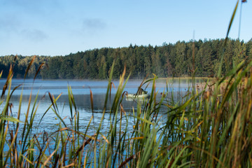 lake landscape, a fisherman in a boat at dawn
