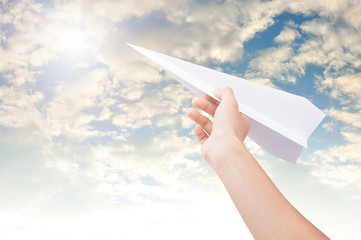 Hand holding paper plane toward cloudy blue sky concept new innovation and new creativity.