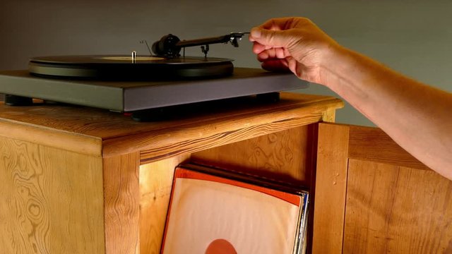 Hand placing the stylus on a long playing record (LP) on a turntable. 