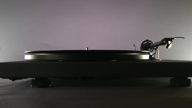 Silhouette shot of hands placing a long playing record (LP) on a turntable. 