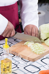 Obraz na płótnie Canvas Chef sliing cabbage on wooden broad