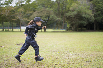 芝生で走る警察の衣装を着た女の子
