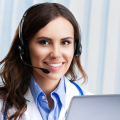 Smiling young doctor in headset, at office