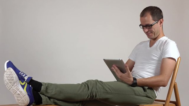 Programmer in black rim glasses using his tablet computer against gray background. Blanc space for adding your graphics or inscriptions. 4K shot