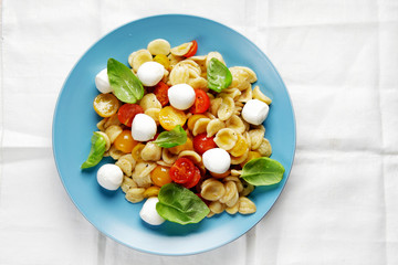 Summer pasta salad of fresh orecchiette with red and yellow toma