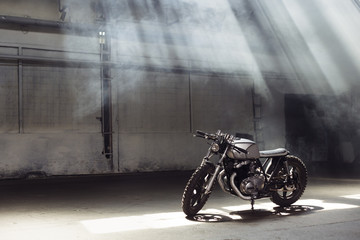 motorcycle standing in dark building in rays of sunlight