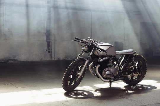Fototapeta motorcycle standing in dark building in rays of sunlight