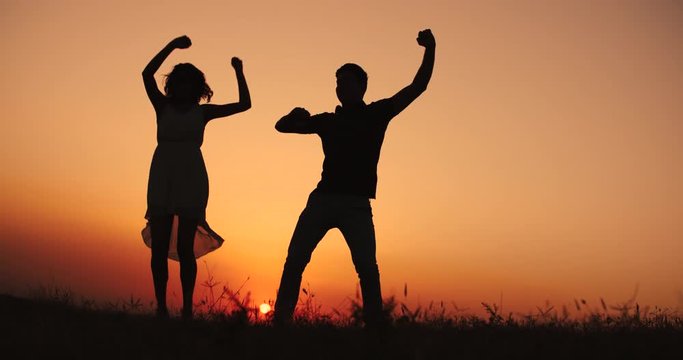 young happy couple having fun dancing on the sunset