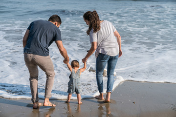 10 month old baby boy walks with mom and dad on the beach