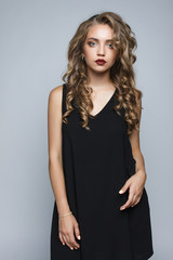 Stylish beautiful girl in a black dress in the studio isolated.