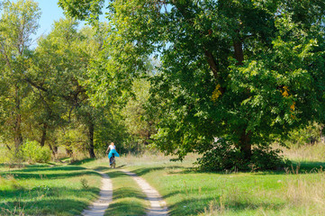 Girl walking with bicycle on the rural road. Summer landscape outdoor countryside. Green park for walk in city