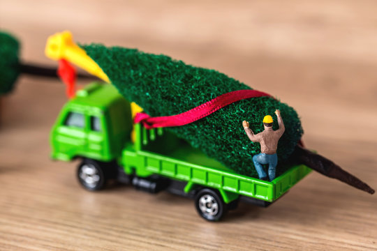 Miniature Worker Passenger Christmas Tree by Truck on Wooden floor ,Determined Image for Christmas Holiday and Happy New Year Gift Celebration concept.
