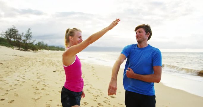 Athletic couple giving each other a High Five on the beach after workout!